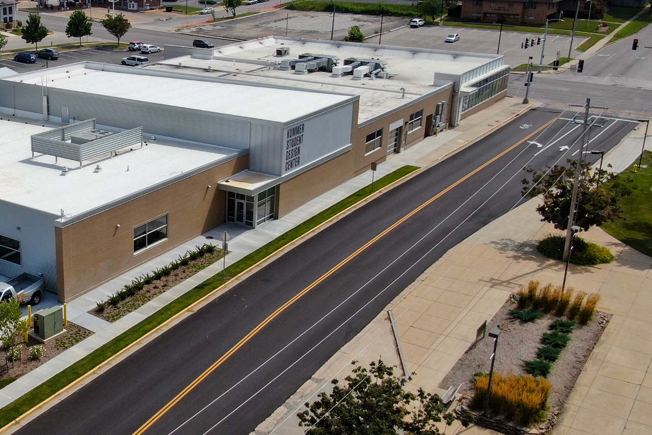 Aerial view of brick building and its rooftop, street and sidewalk.